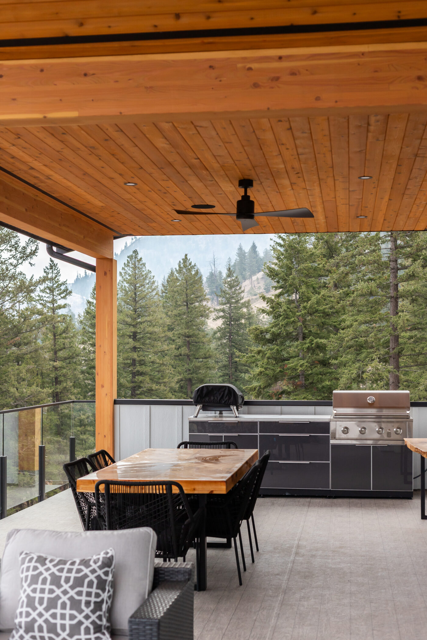 Covered outdoor deck with wood soffit ceiling and ceiling fan in custom Kamloops home