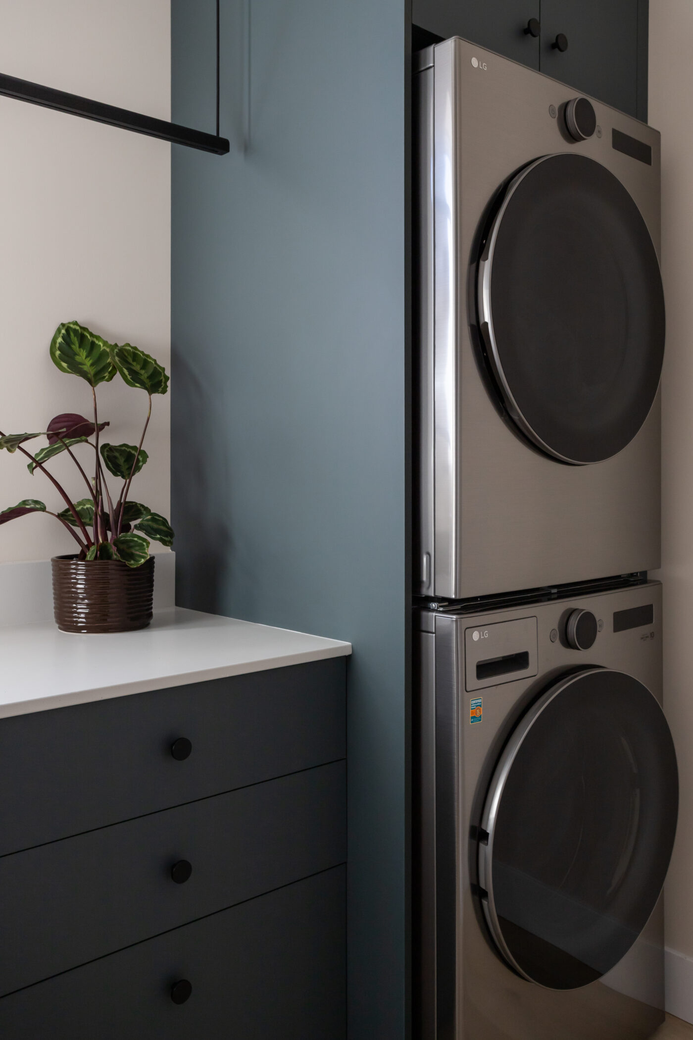 Stylish laundry room with front-load washer, custom cabinetry, and quartz countertop